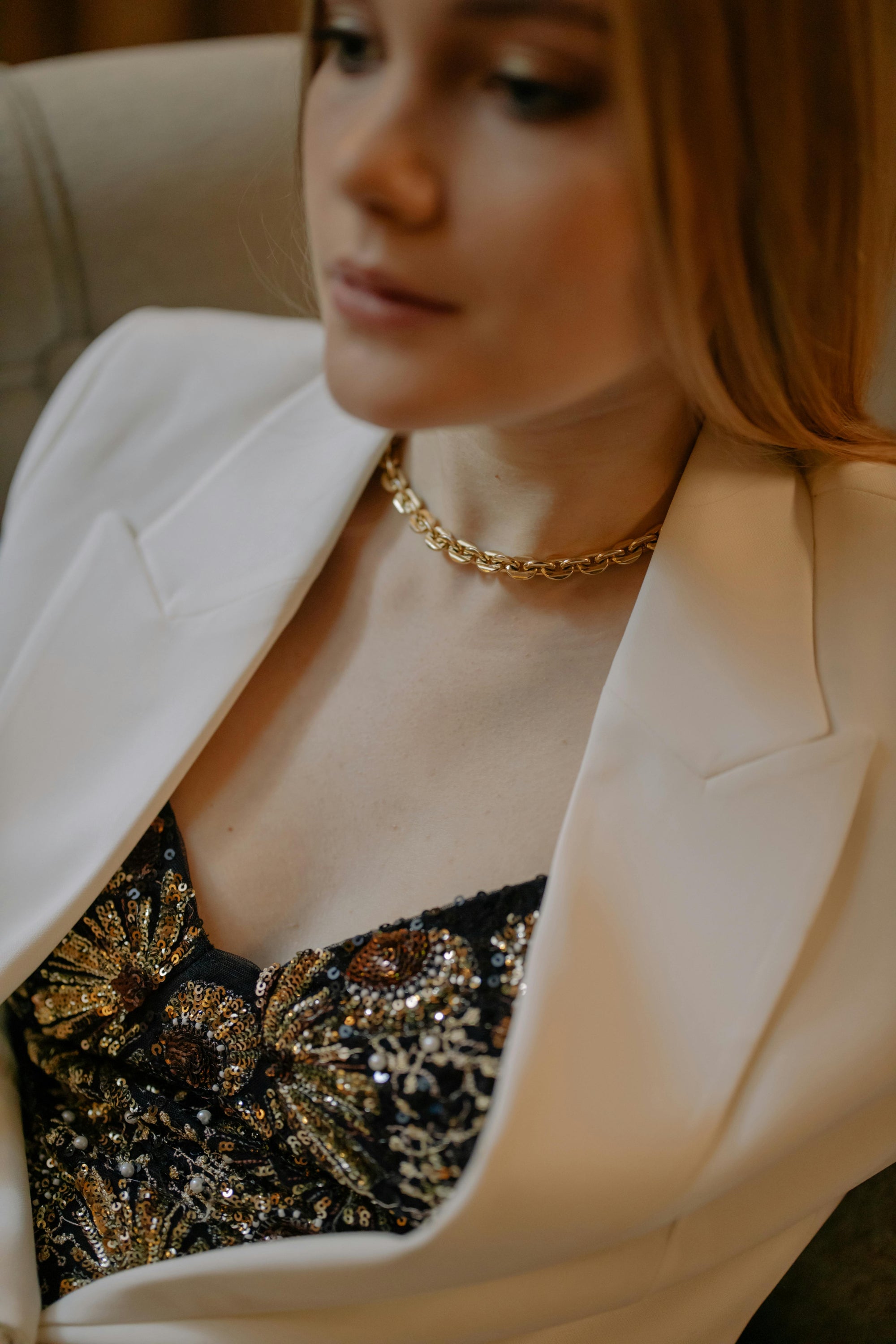 Femme avec collier doré et veste blanche 
